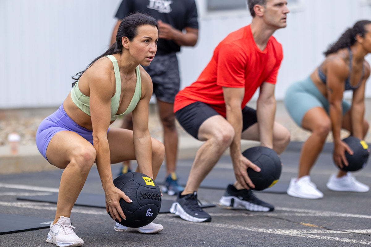 team doing trx medicine ball squats