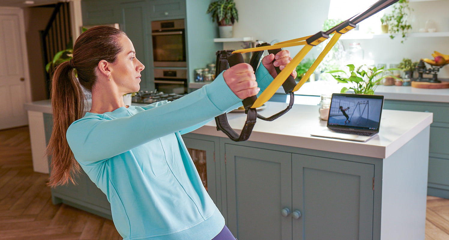 Woman using TRX Suspension Trainer and TRX Training Club in her home