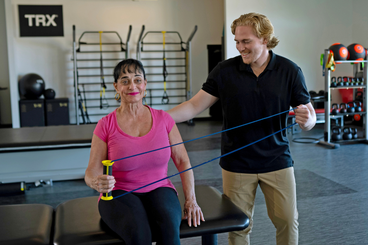 Senior performing chair exercises at home, including a seated leg extension and biceps curl for strength, mobility, and balance.