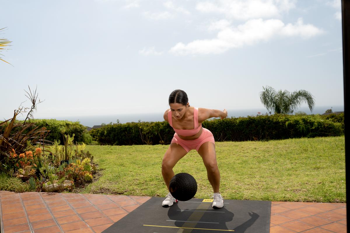 female trainer throwing slam ball