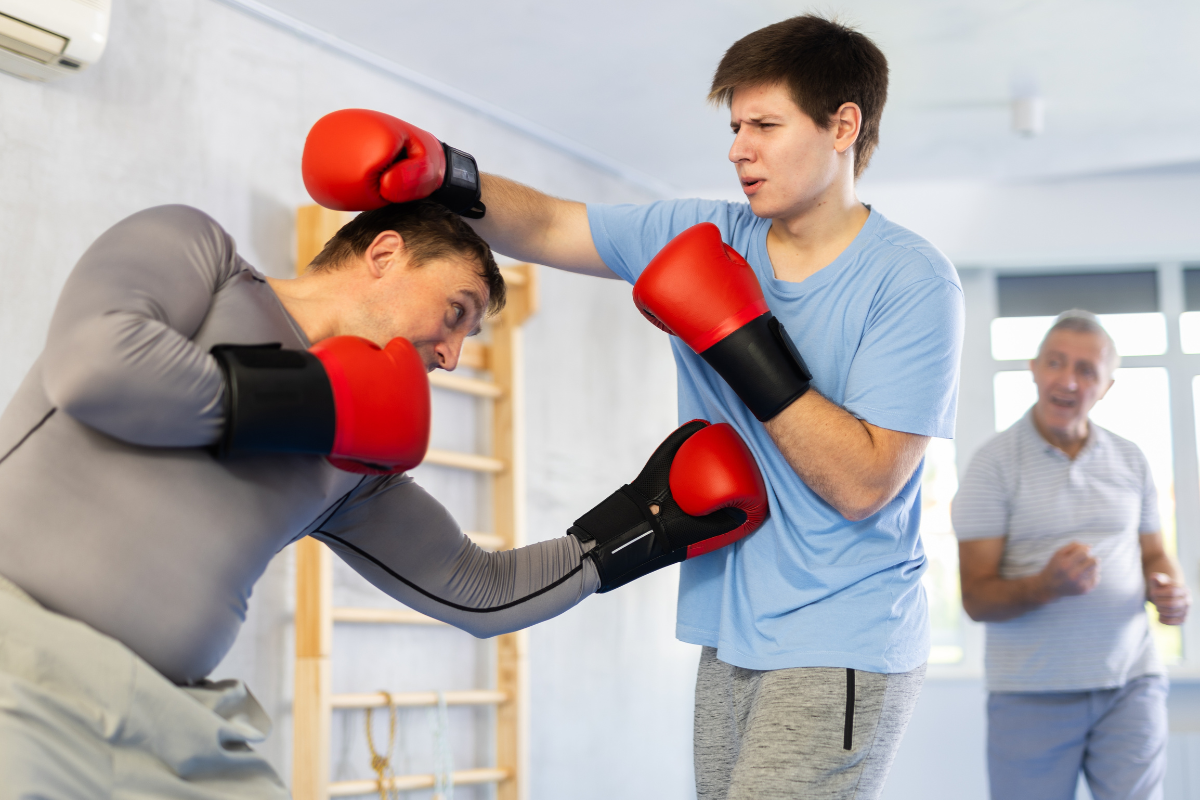 Young man and adult man training boxing punches in home