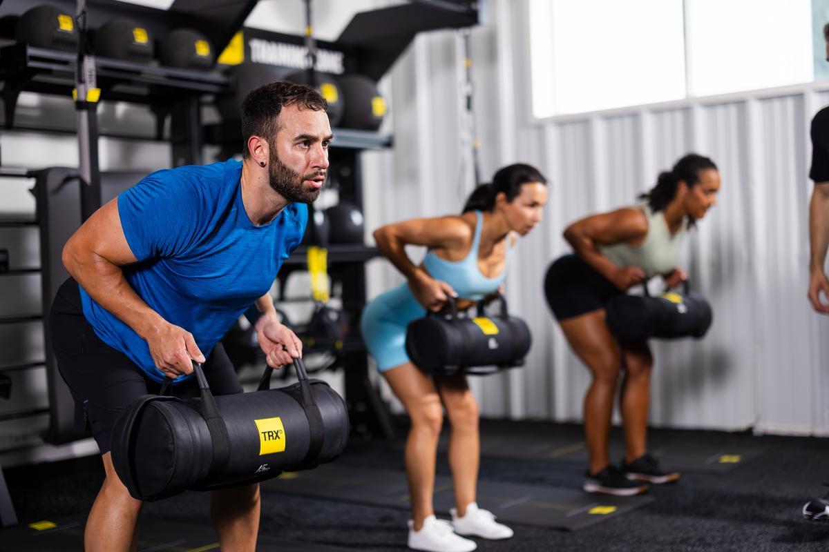 trainers doing trx weighted bag exercises