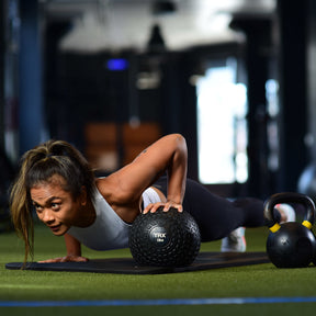 female trainer doing pushup with trx slam ball